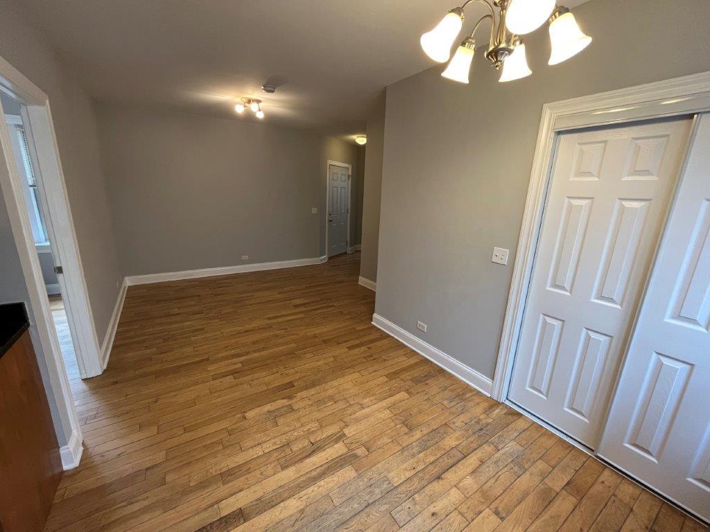 4548 West George Street, Unit 2 Chicago, IL 60641 - Photo 3 of 9 a view of an empty room with wooden floor and a window