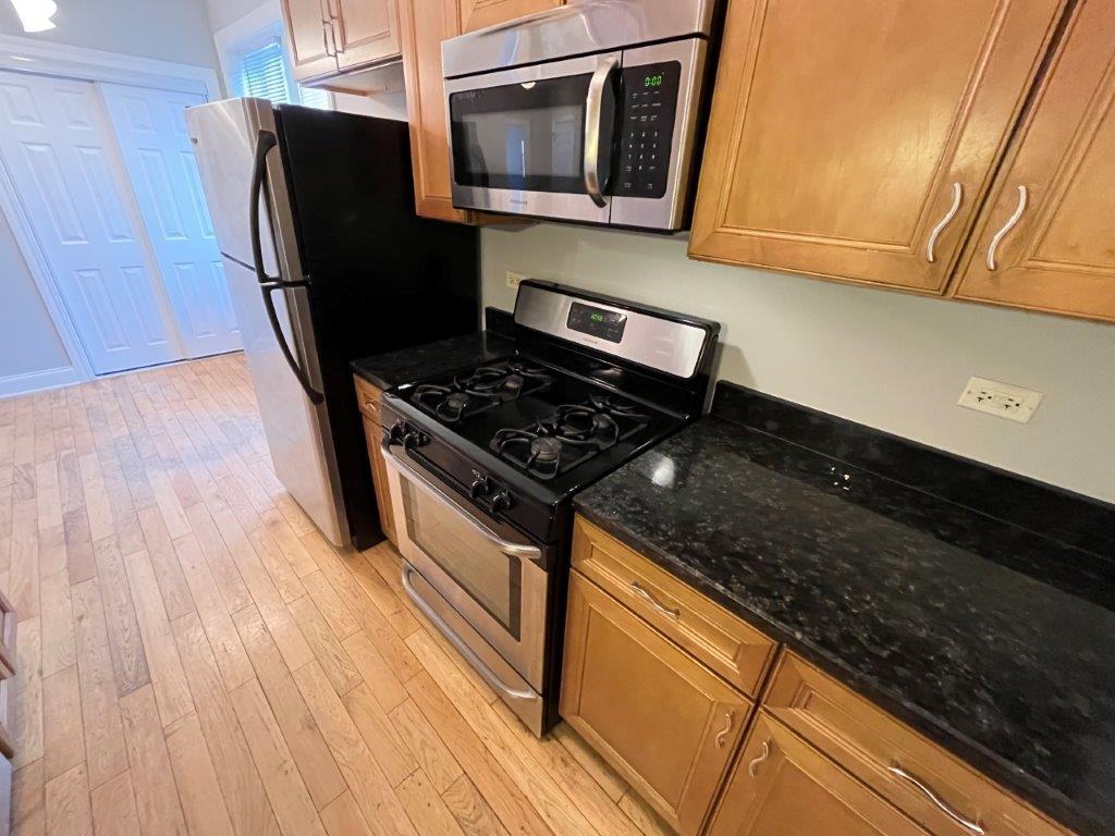 4548 West George Street, Unit 2 Chicago, IL 60641 - Photo 5 of 9 a kitchen with granite countertop wooden cabinets and stainless steel appliances
