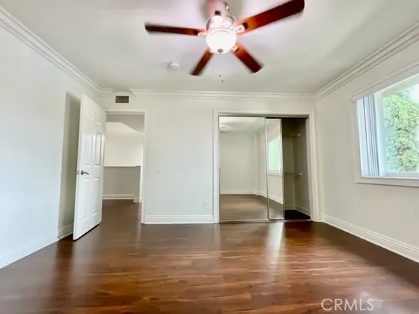 a view of empty room with wooden floor and fan