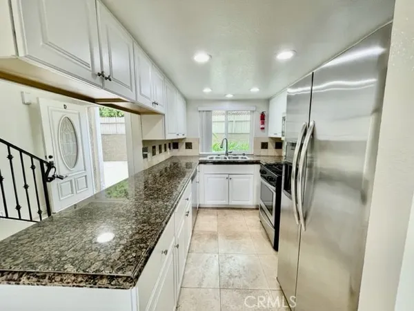 a kitchen with stainless steel appliances granite countertop a sink refrigerator and cabinets