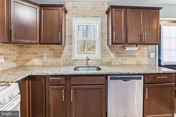 a kitchen with granite countertop stainless steel appliances a sink and cabinets