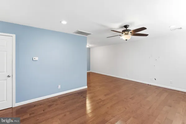 an empty room with wooden floor chandelier fan and windows