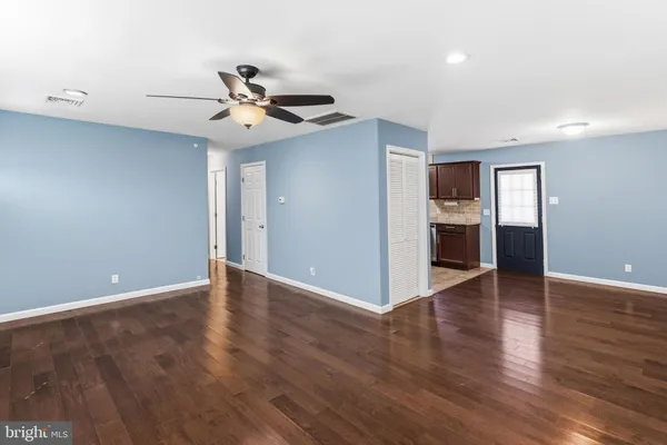a view of an empty room with wooden floor and a ceiling fan