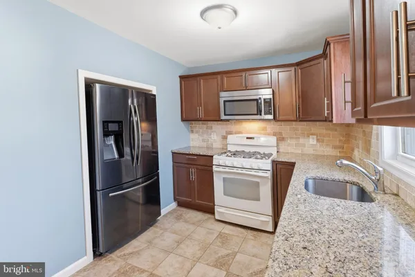 a kitchen with granite countertop a refrigerator stove and microwave