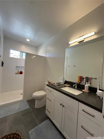 a bathroom with a granite countertop sink a toilet a mirror and shower