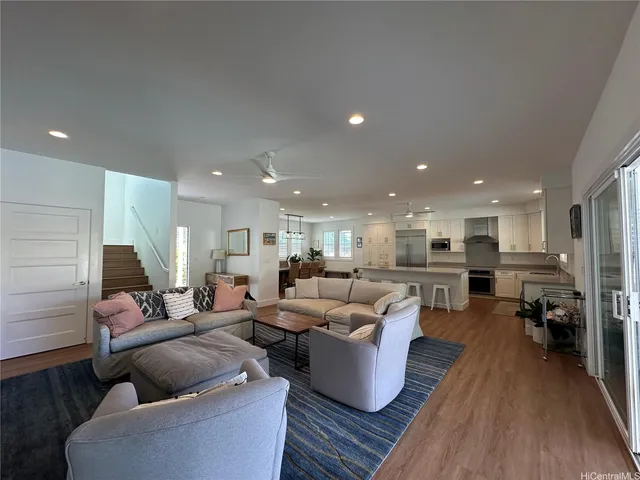 a living room with furniture kitchen view and a wooden floor