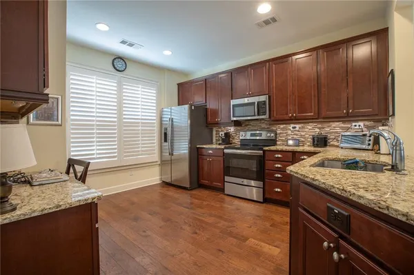 a kitchen with stainless steel appliances granite countertop a stove a sink dishwasher a refrigerator and a microwave oven