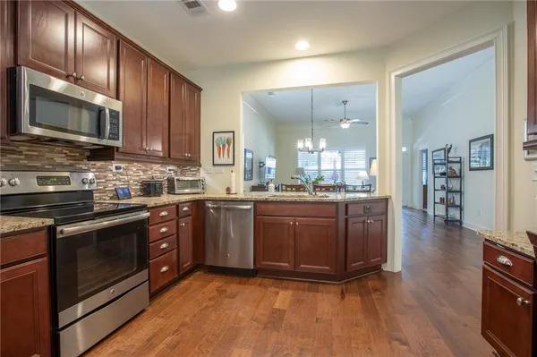 a kitchen with stainless steel appliances granite countertop wooden cabinets and a stove top oven