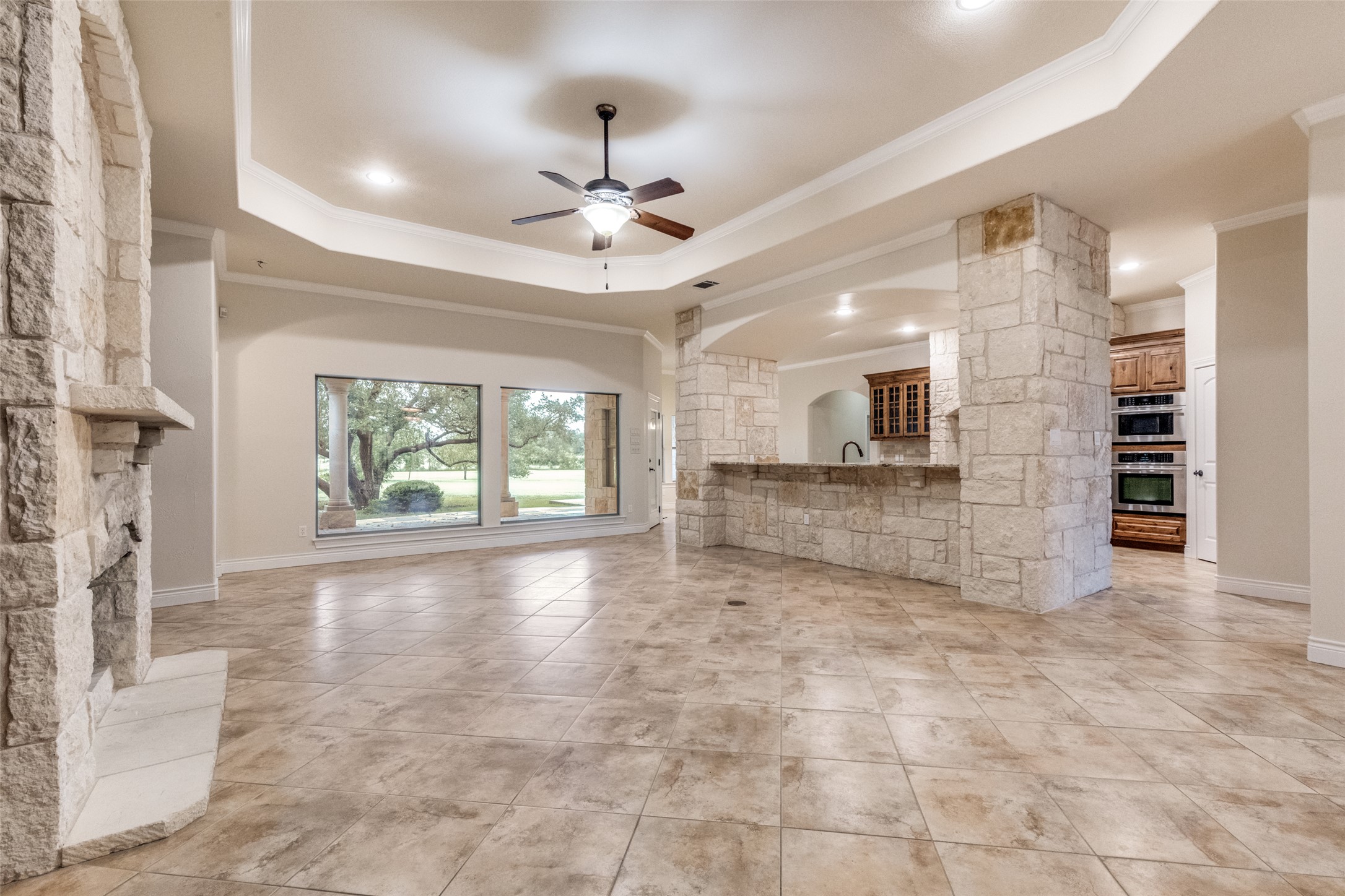 101 Copper Leaf Court Georgetown, TX 78633 - Photo 9 of 31 Spacious interior featuring stone-clad columns and fireplace, large format tile flooring, and broad picture windows