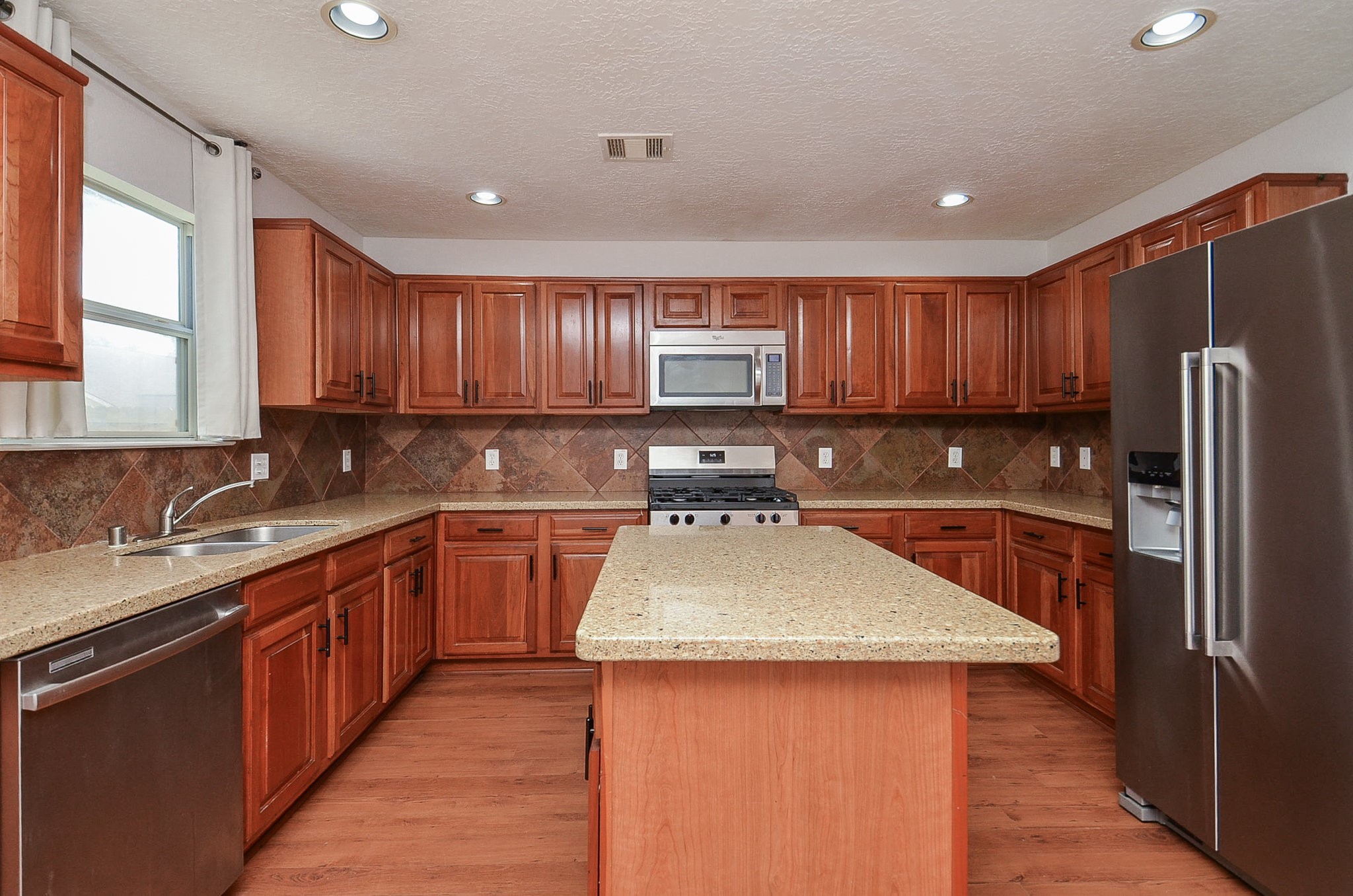 29610 Benson Springs Lane Spring, TX 77386 - Photo 11 of 25 a kitchen with stainless steel appliances wooden cabinets a sink and a stove