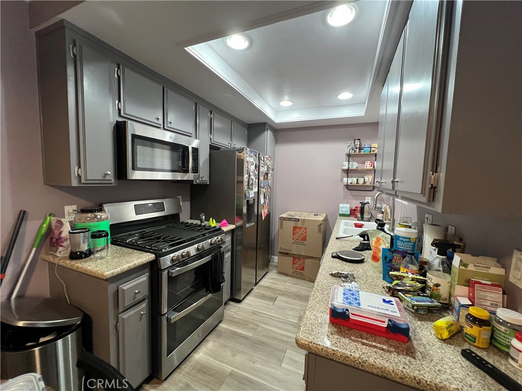 1111 Packers Circle, Unit 25 Tustin, CA 92780 - Photo 5 of 10 a kitchen with kitchen island granite countertop a sink wooden cabinets and stainless steel appliances