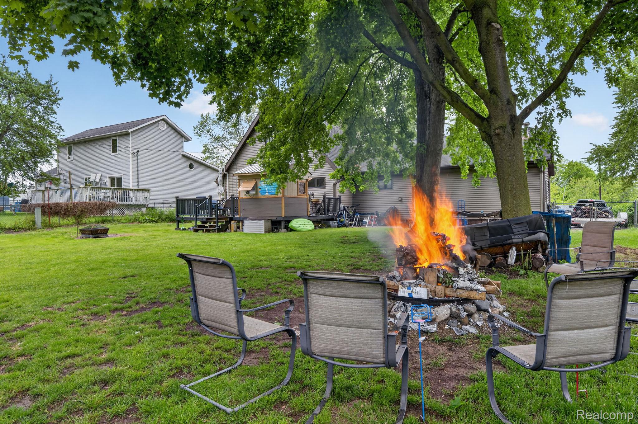 1280 Petts Road Fenton, MI 48430 - Photo 40 of 62 View of green lawn featuring an outdoor fire pit and a wooden deck