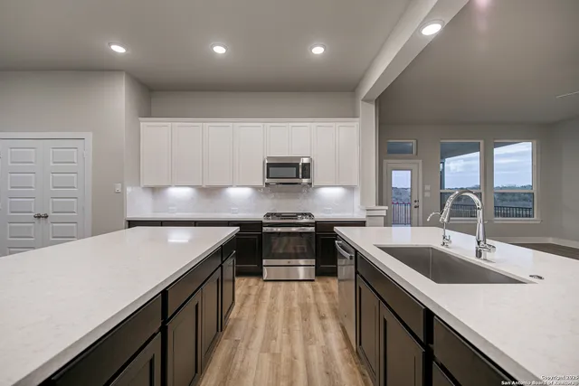 a kitchen with stainless steel appliances granite countertop a sink dishwasher and a stove with wooden floor
