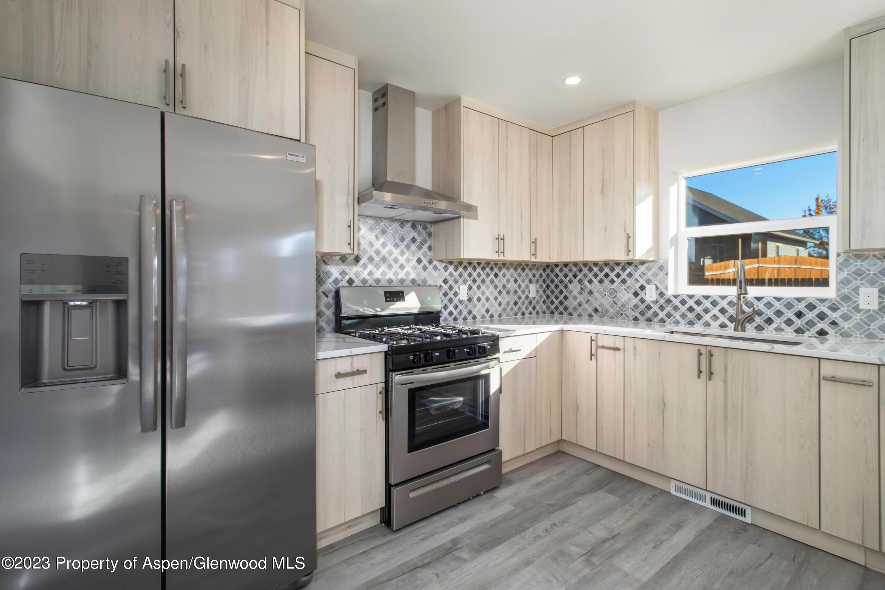 1762 Belgian Loop Silt, CO 81652 - Photo 4 of 18 a kitchen with stainless steel appliances granite countertop a refrigerator a sink a stove and white cabinets with wooden floor