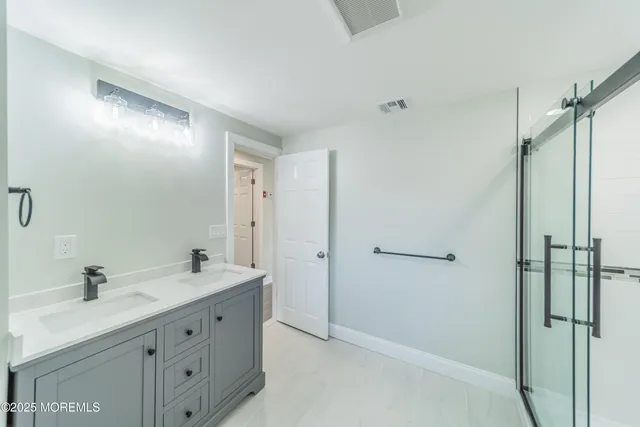 a spacious bathroom with a double vanity sink a mirror and a shower