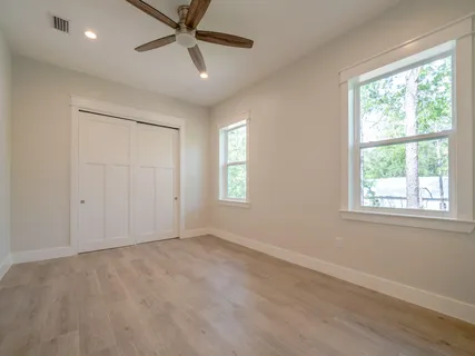 an empty room with wooden floor and windows
