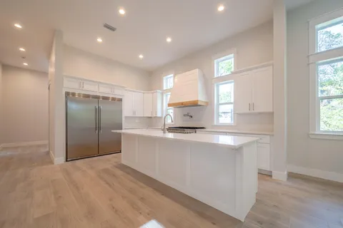 a large kitchen with stainless steel appliances a sink a refrigerator and window