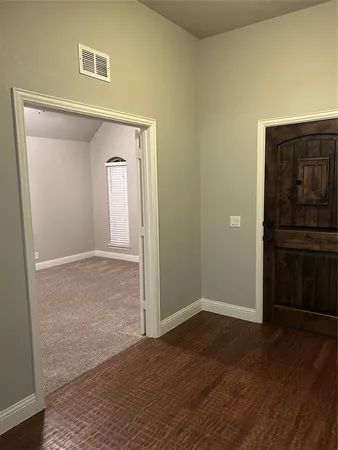 a view of an empty room with wooden floor and closet