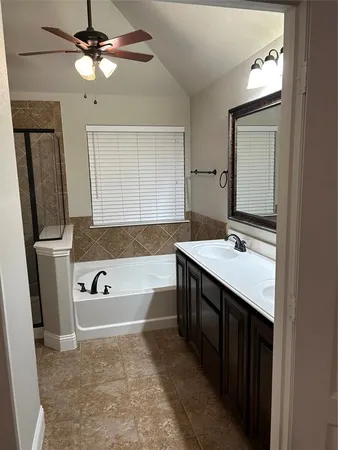 a spacious bathroom with a tub sink and mirror