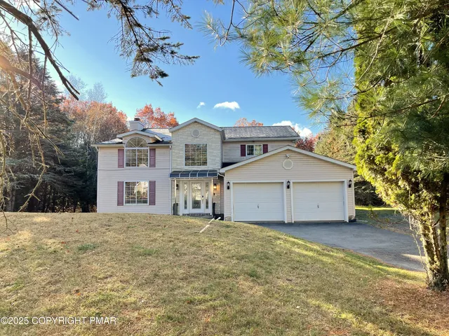 a view of a house with a large tree and a yard
