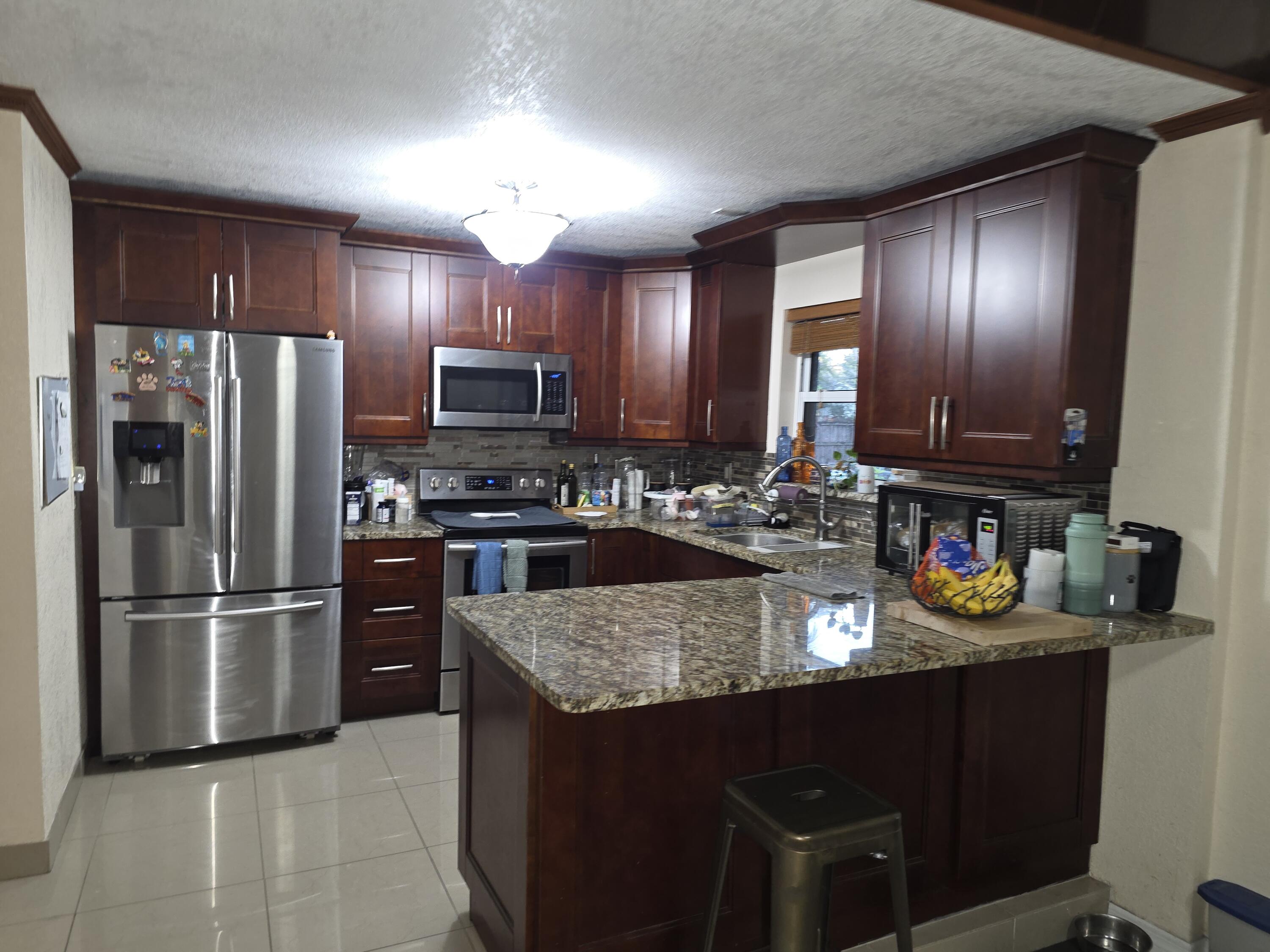 4118 Ruth Road Lake Worth, FL 33461 - Photo 2 of 21 a kitchen with stainless steel appliances granite countertop a refrigerator stove and microwave