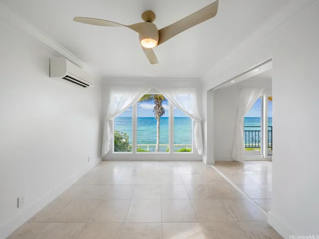 an empty room with windows and chandelier fan