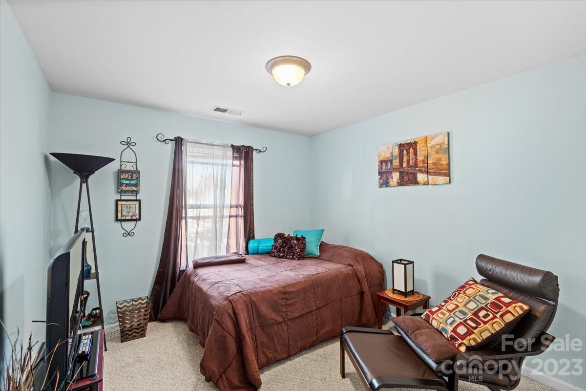 13004 Rothe House Road Charlotte, NC 28273 - Photo 15 of 27 a bedroom with a bed and a bookshelf with wooden floor