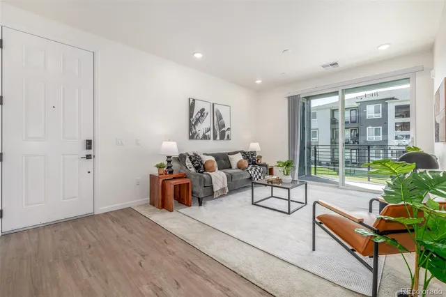 a living room with furniture and large windows with garden view