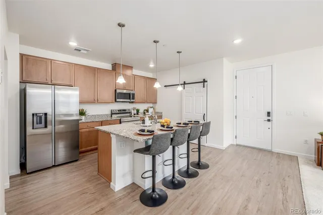 a kitchen with stainless steel appliances granite countertop a refrigerator a sink dishwasher a stove and white cabinets with wooden floor