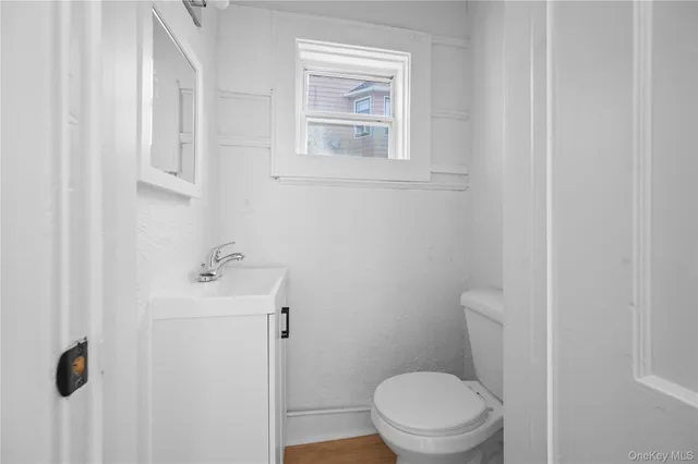 a bathroom with a toilet a sink a window and mirror