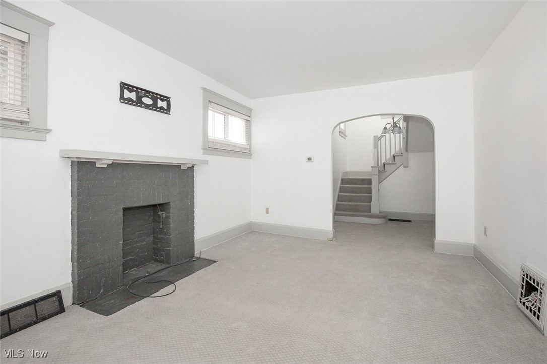 1604 Hampton Road Akron, OH 44305 - Photo 13 of 30 Unfurnished living room with light carpet, stairs, a brick fireplace, and arched walkways
