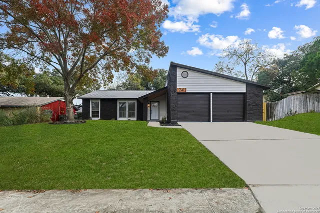 a front view of a house with a garden and trees