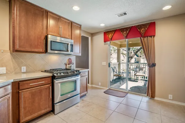 a kitchen with stainless steel appliances granite countertop a stove a sink and a microwave