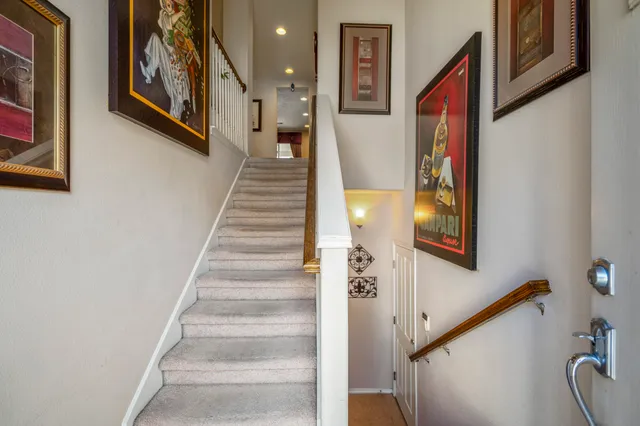a view of staircase with lots of frames on wall and a wall painting