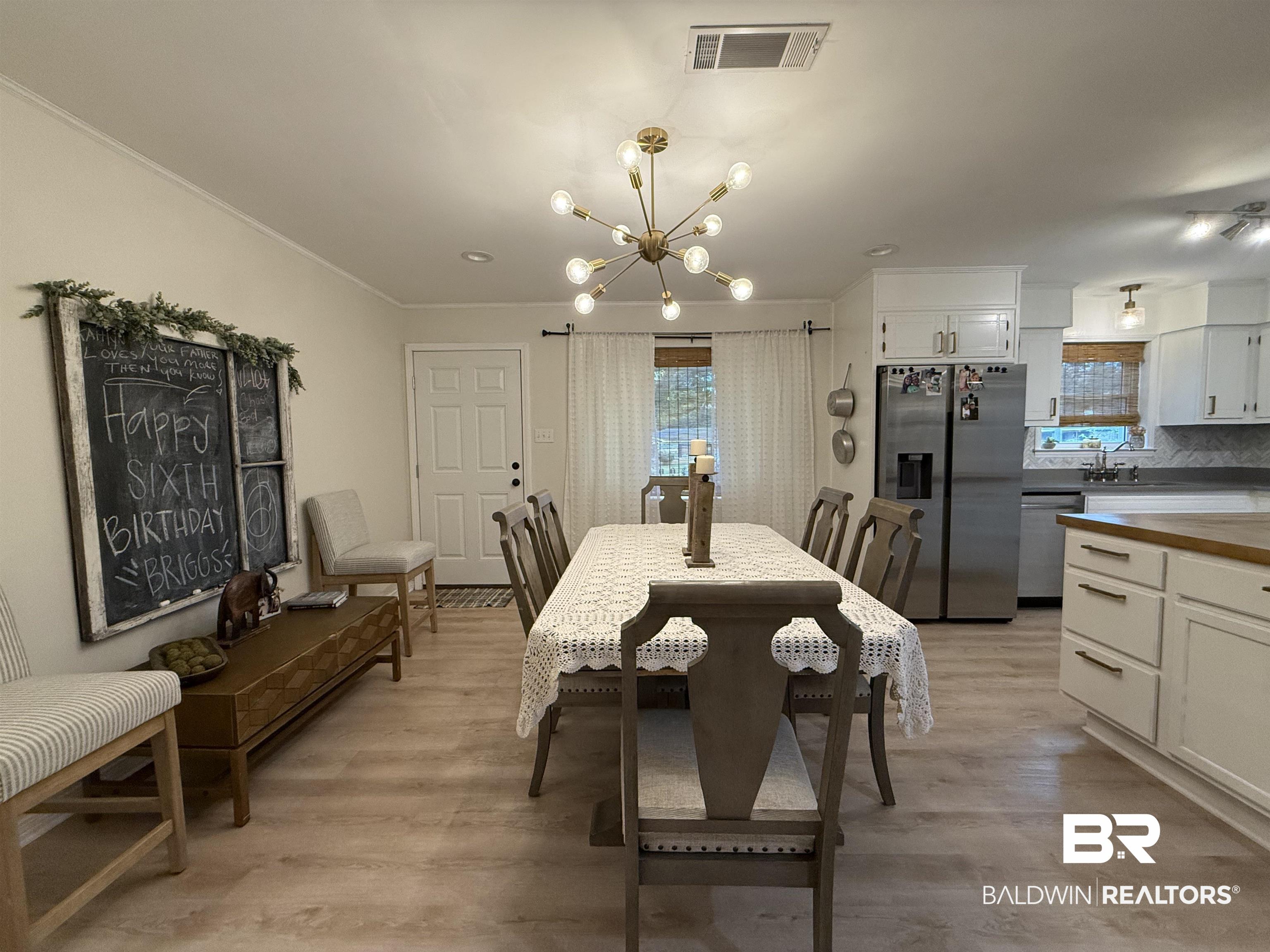 90 Florida Street Monroeville, AL 36460 - Photo 23 of 31 Dining space with a notable chandelier, ornamental molding, and light wood-look vinyl plank flooring