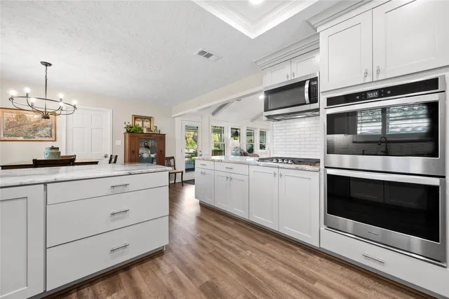 a kitchen with stainless steel appliances granite countertop white cabinets a stove a sink and dishwasher