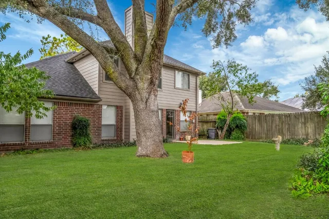 a view of a house with backyard and a tree