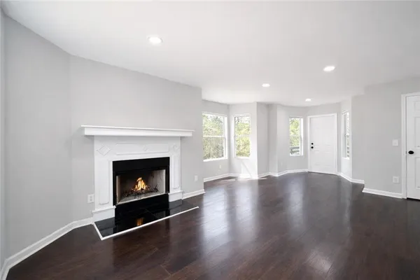 a view of an empty room with wooden floor fireplace and a window