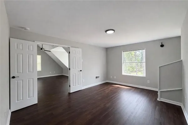 a view of an empty room with wooden floor and a window