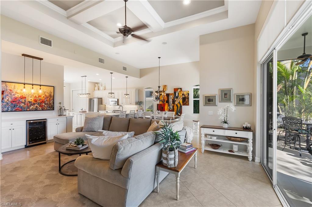 12612 Grandezza Circle Estero, FL 33928 - Photo 18 of 48 Living room featuring a high ceiling, coffered ceiling, ceiling fan with notable chandelier, and beverage cooler