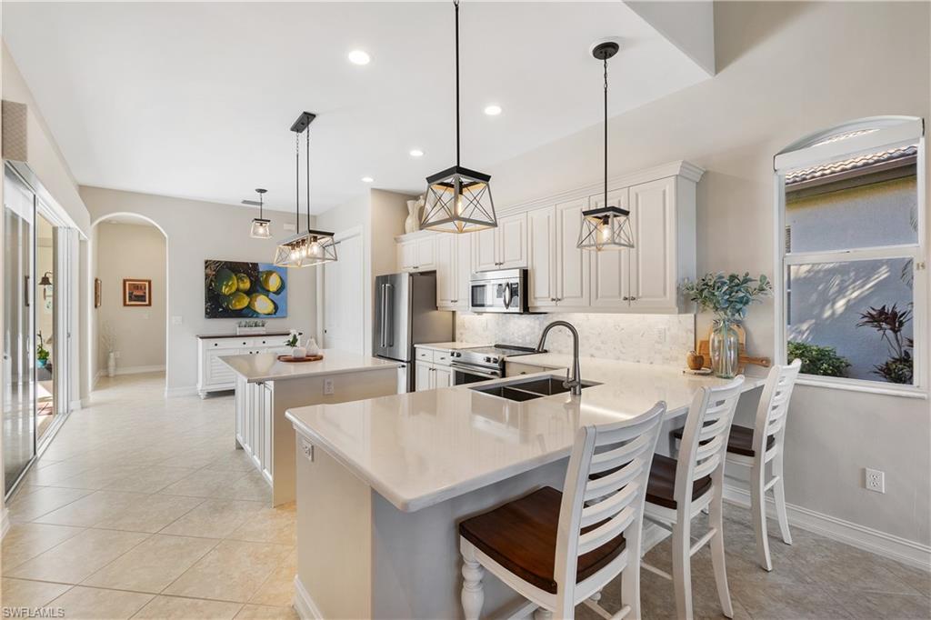 12612 Grandezza Circle Estero, FL 33928 - Photo 20 of 48 Kitchen featuring tasteful backsplash, a breakfast bar area, hanging light fixtures, kitchen peninsula, and stainless steel appliances