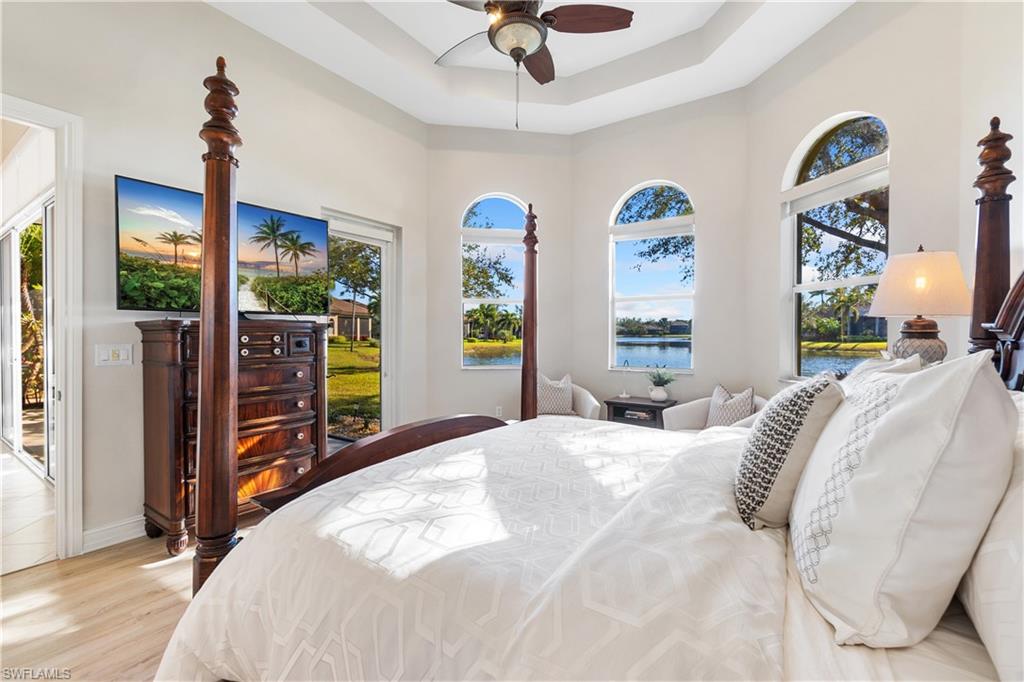 12612 Grandezza Circle Estero, FL 33928 - Photo 27 of 48 Bedroom featuring access to exterior, a tray ceiling, ceiling fan, and light wood-type flooring