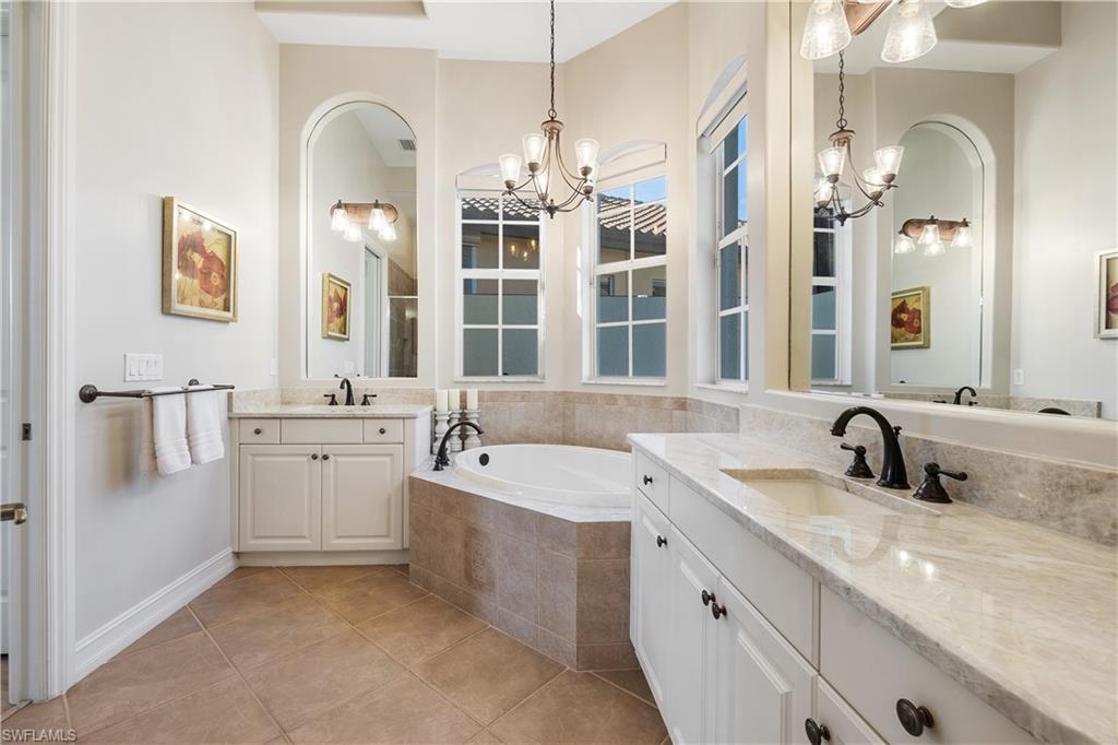 12612 Grandezza Circle Estero, FL 33928 - Photo 29 of 48 Bathroom featuring tile patterned flooring, vanity, tiled bath, and a notable chandelier