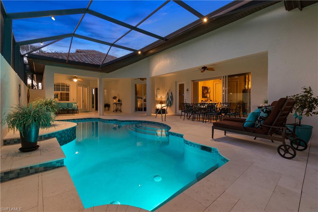 12612 Grandezza Circle Estero, FL 33928 - Photo 45 of 48 Pool at dusk with ceiling fan, a patio area, and glass enclosure