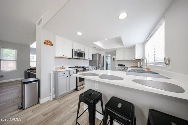 a kitchen that has a sink a stove and chairs