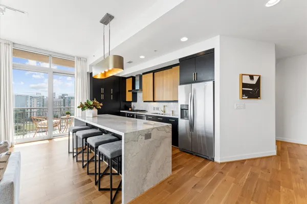a kitchen with stainless steel appliances a dining table chairs stove refrigerator and cabinets