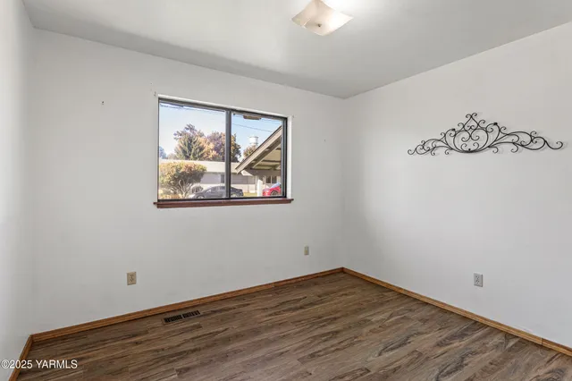 a view of an empty room with wooden floor and closet