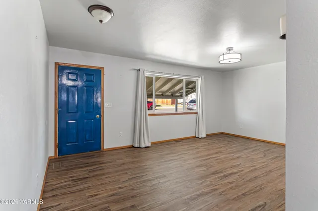 an empty room with wooden floor cabinet and mirror