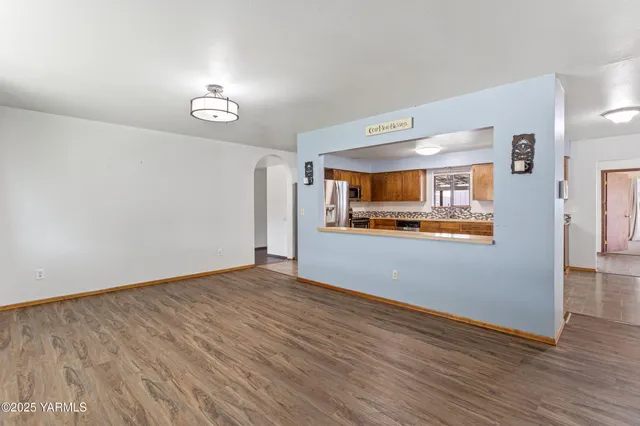 an empty room with wooden floor and a kitchen