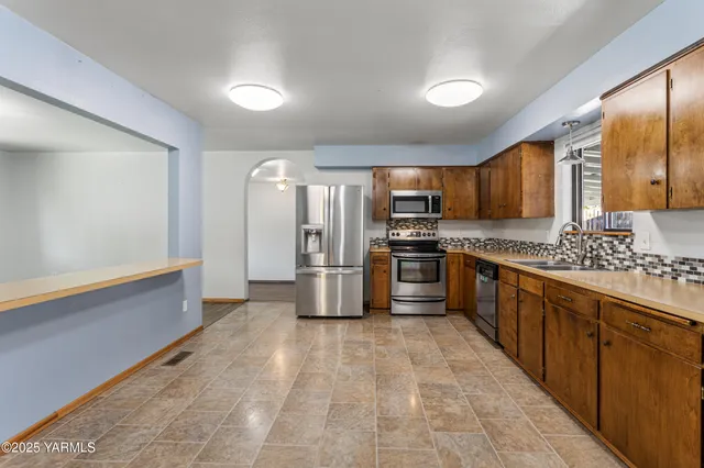 a large kitchen with stainless steel appliances cabinets a sink and a counter top space